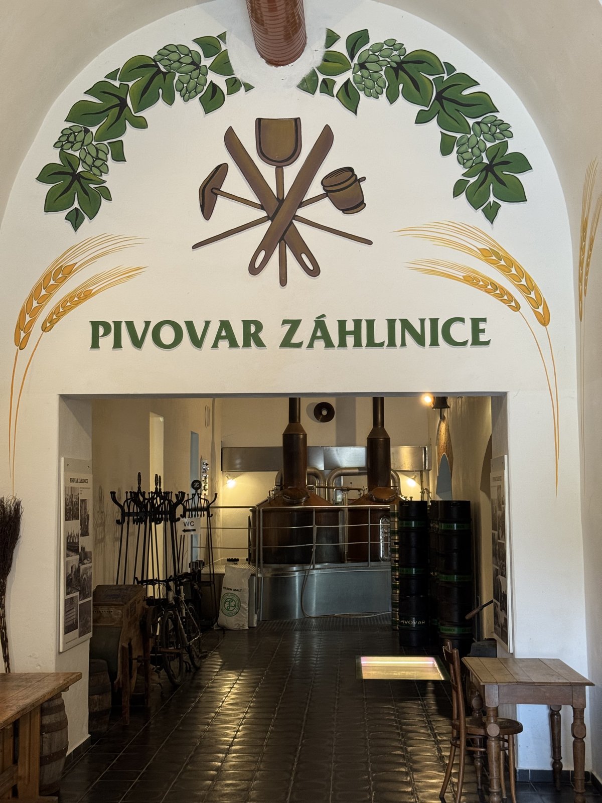 Interiér pivovaru Záhlinice s varnou technologií a vstupním obloukem s logem pivovaru