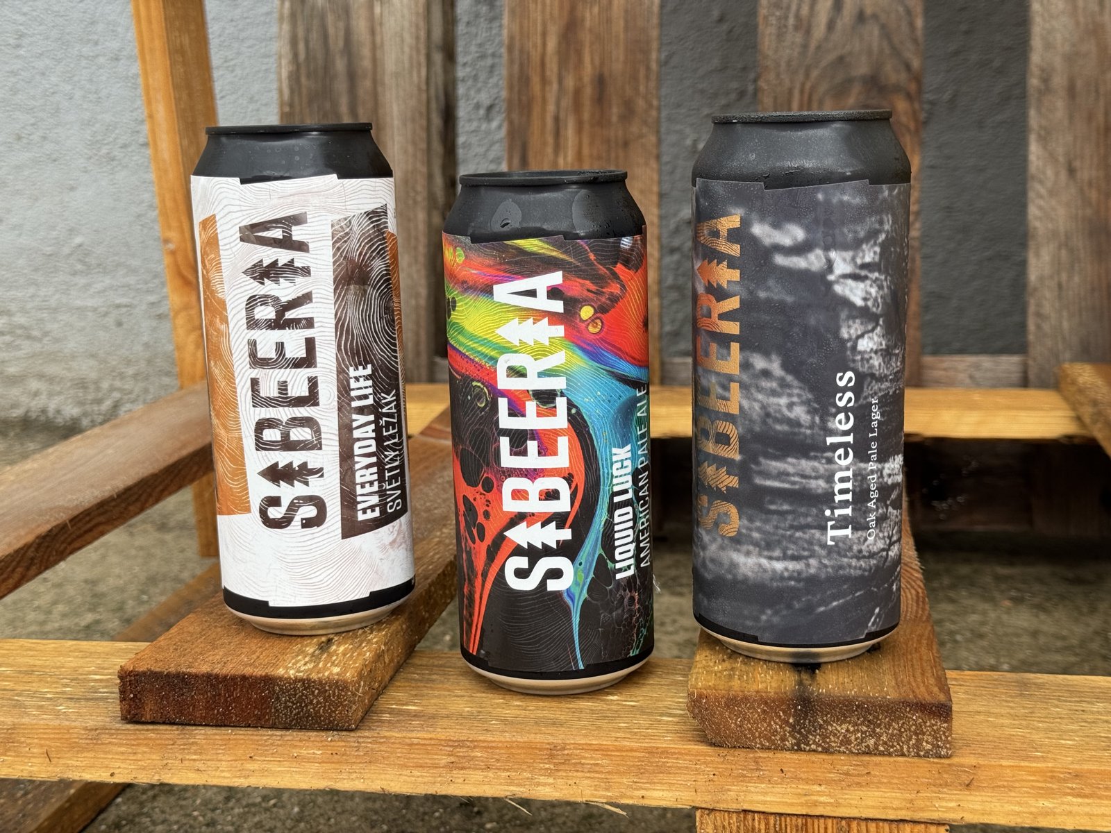 Tři plechovky na paletě. Průmyslové prostředí, žádné kudrlinky. Hlavní je obsah.