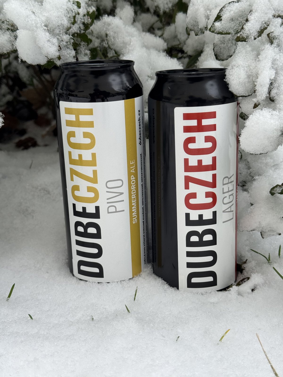 Dva vzorky z pivovaru DubeCzech připravené na zimní test. Sníh chladí, etikety kontrastují a pivo čeká, až přijde jeho chvíle ve vlaku.