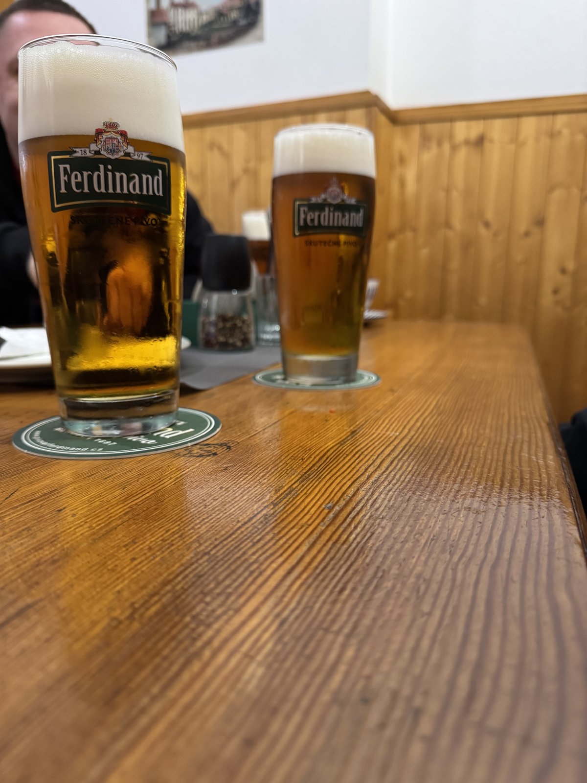 Sklenice piva Ferdinand na dřevěném stole v hospodě