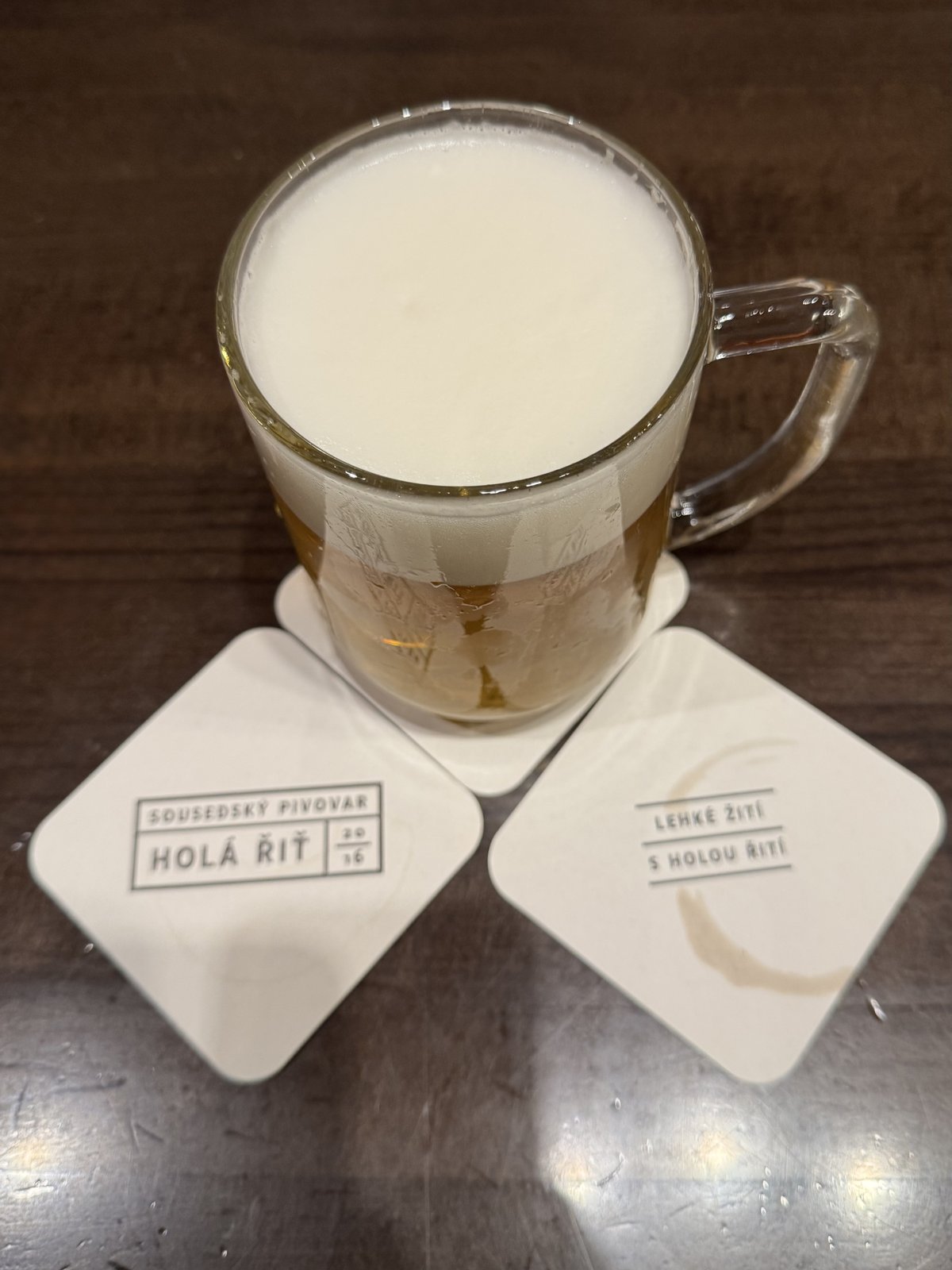 Detail sklenice piva Holá řiť na podtáccích s logem sousedského pivovaru Holá řiť