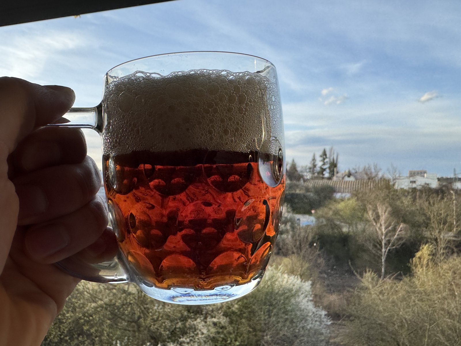 Sklenice s červeným pivem proti světlu s pěnou