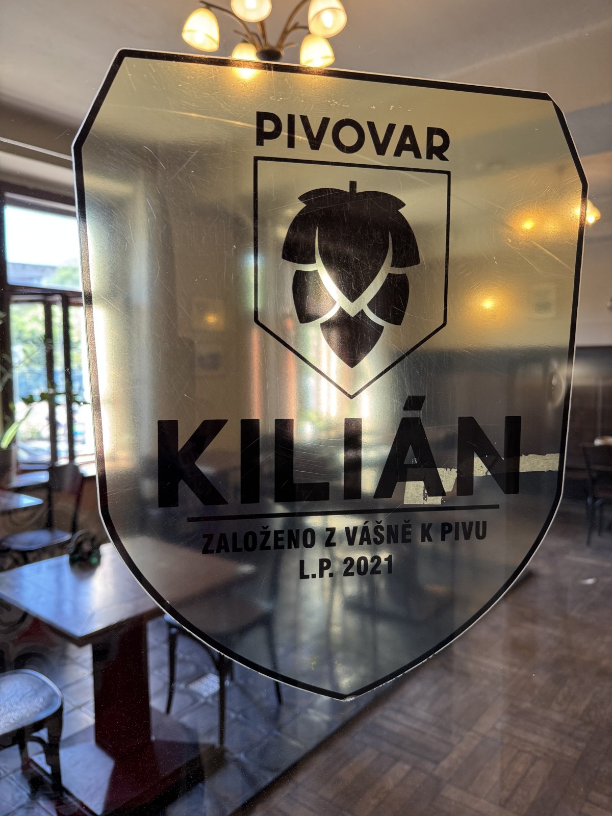 Logo pivovaru Kilián na skle restaurace v Praze Libni