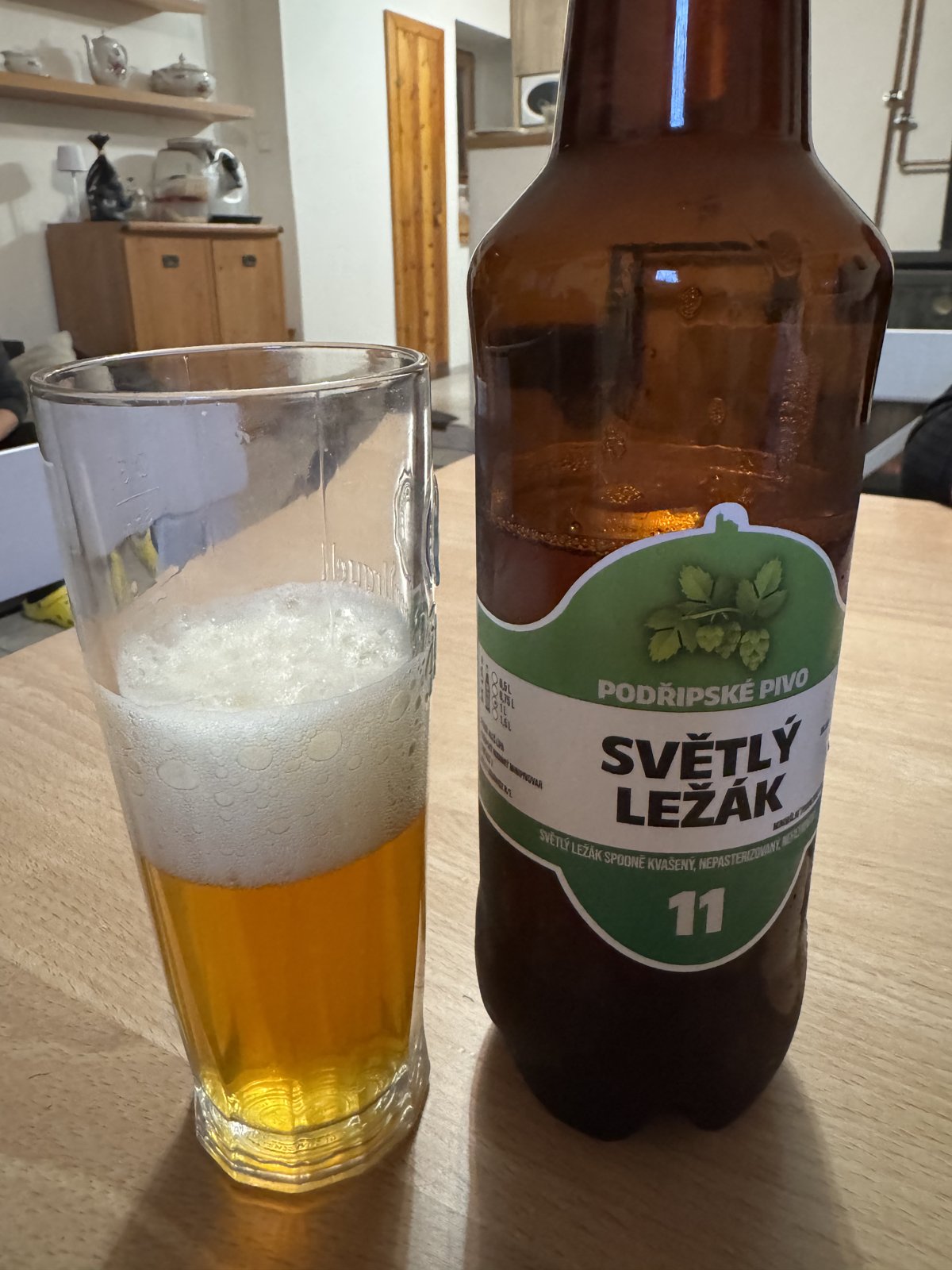 Světlý ležák z Podřípského pivovaru nalitý ve sklenici vedle otevřené lahve
