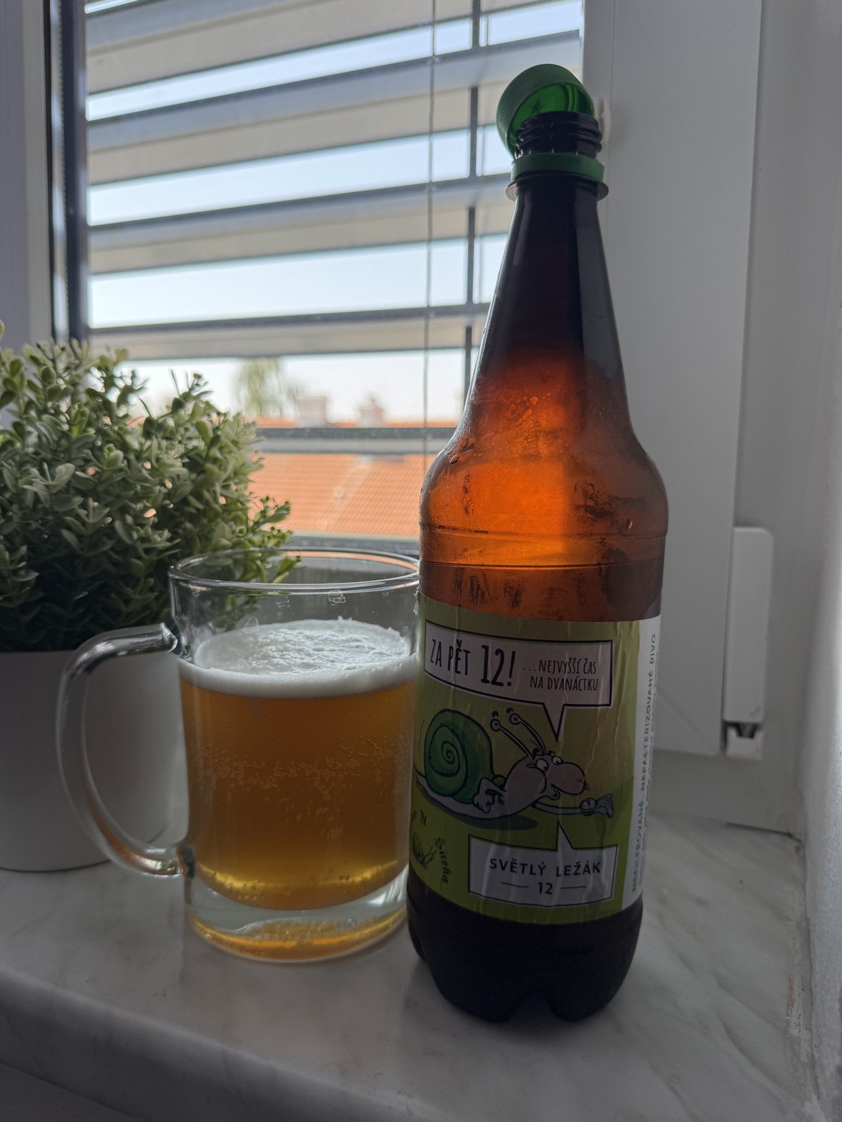 Láhev světlého ležáku 12° z Pivovaru U šneka vedle sklenice světlého piva