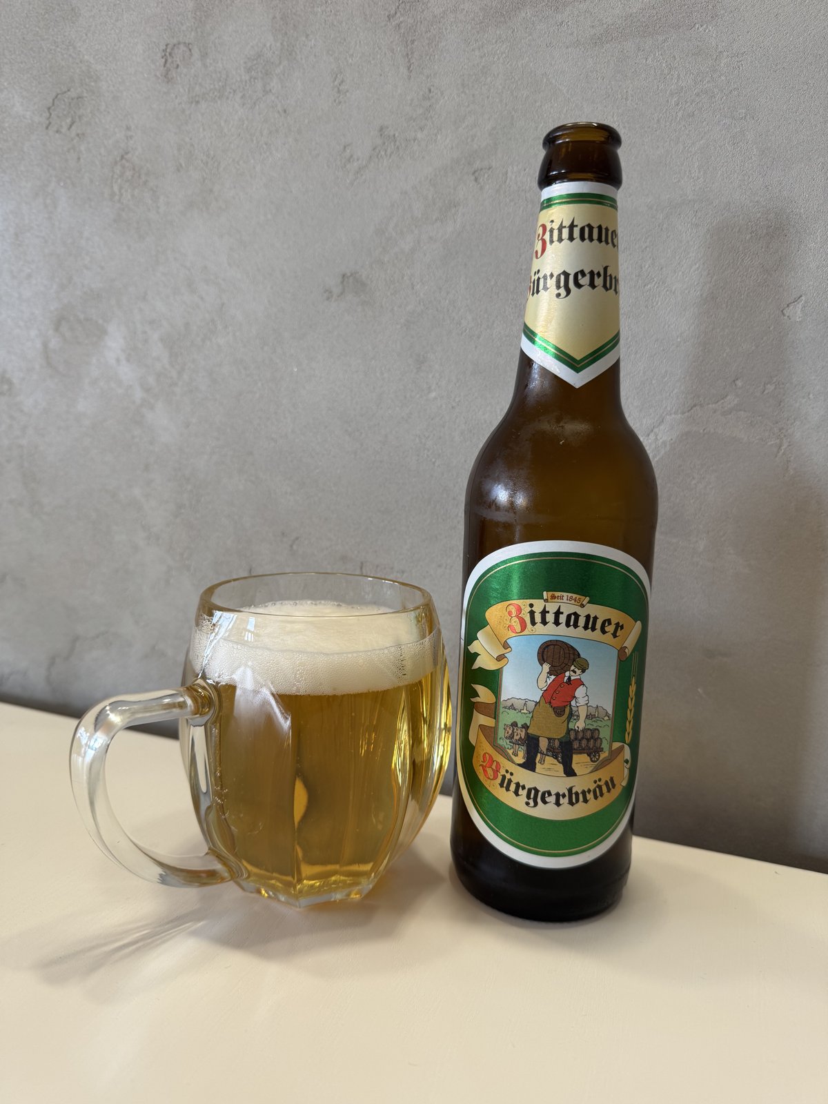 Láhev německého piva Bittauer Bürgerbräu a sklenice s natočeným pivem